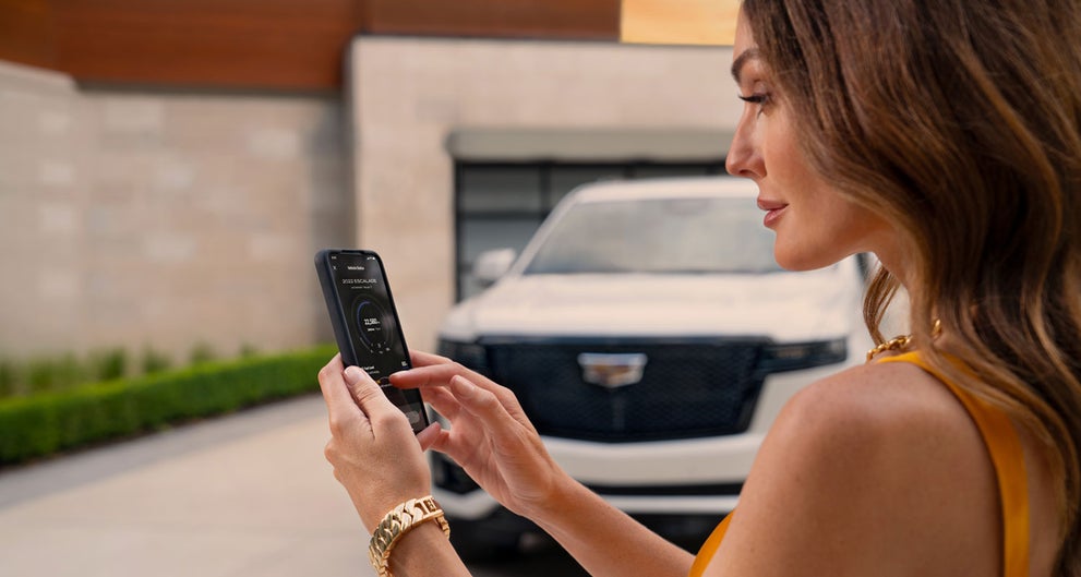 lady checking her mobile with a Cadillac vehicle background | Fitzgerald Cadillac Annapolis in Annapolis MD
